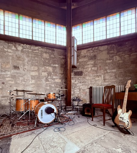 A four-piece drum set and a bass guitar in a church.