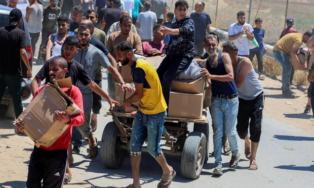 Palestinos caminan con ayuda recibida de la Fundación Humanitaria de Gaza, respaldada por Estados Unidos, en el centro de la Franja, el 29 de mayo de 2025. (Ramadan Abed / Reuters)