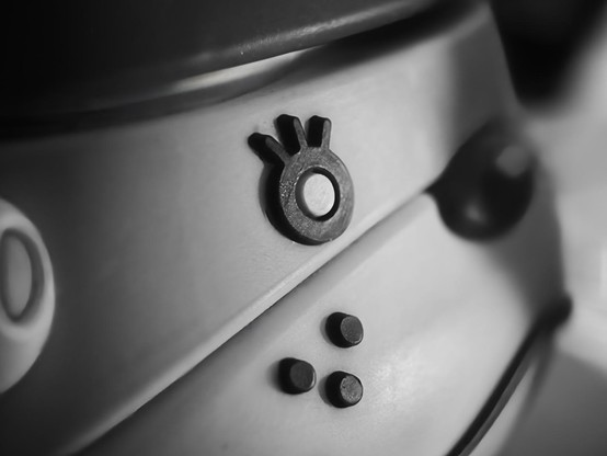Macro photo of a plastic AirPods case in the shape of Lottie's head from Animal Crossing. The eye is centered in sharp detail while the edges blur gently and have a slight vignette. The photo is in black and white.