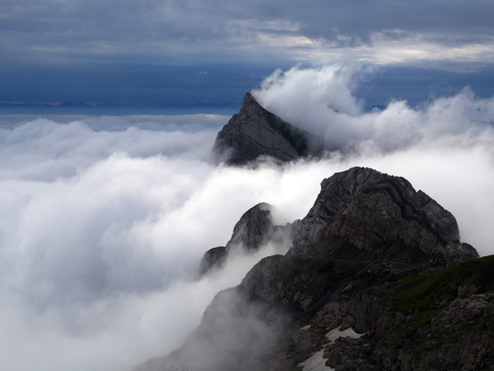 Aus der tief liegenden Wokendecke ragen die Gipfel des Alpsteins teilweise heraus, im Hintergrund ist dunkel der Alpenhauptkamm zu erkennen.